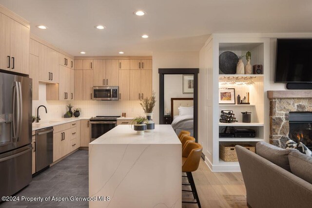 kitchen featuring a center island, a stone fireplace, dark hardwood / wood-style floors, a breakfast bar area, and appliances with stainless steel finishes