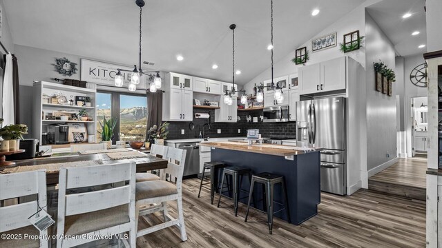 450 E 10th St, Rifle, CO 81650 - kitchen featuring open shelves, a kitchen bar, a center island, stainless steel appliances, and wood counters