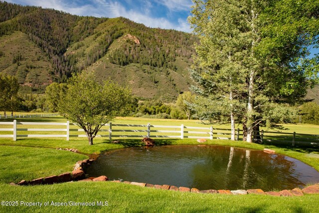 view of home's community featuring a water and mountain view, a yard, and a rural view