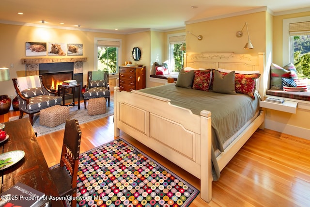 bedroom with multiple windows, crown molding, and light hardwood / wood-style floors