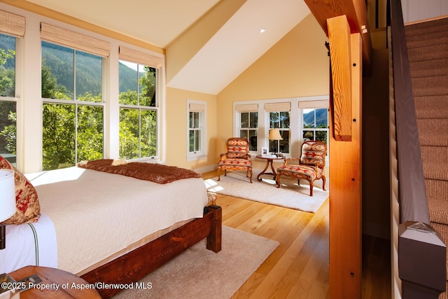 bedroom featuring high vaulted ceiling, multiple windows, and light wood-type flooring