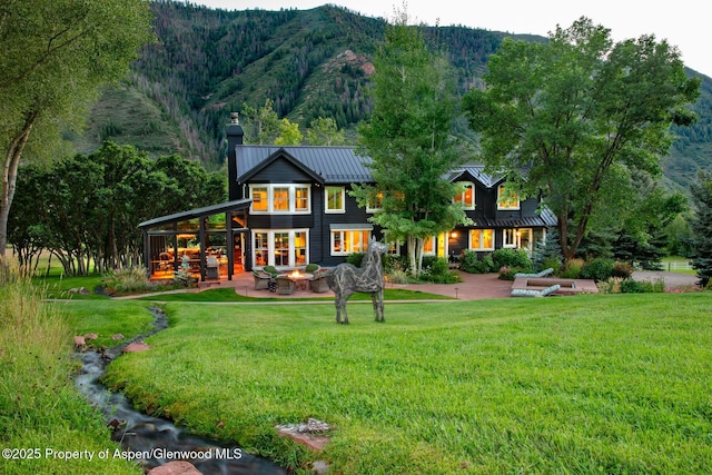 back of property with a mountain view, a lawn, and a patio