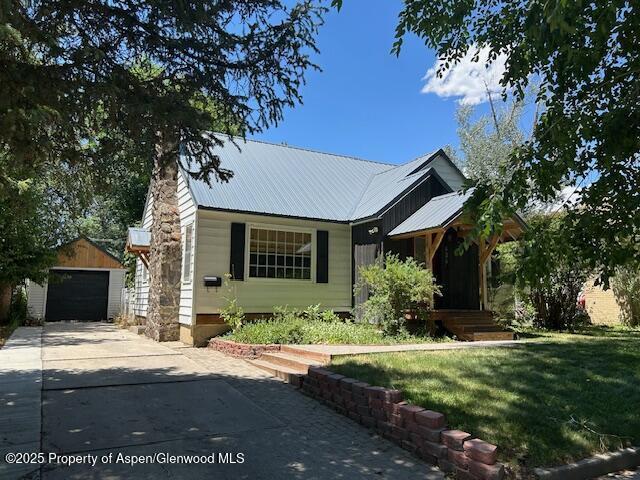 624 Barclay St, Craig, CO 81625 - view of front facade with concrete driveway, an outbuilding, a metal roof, a garage, and a front yard