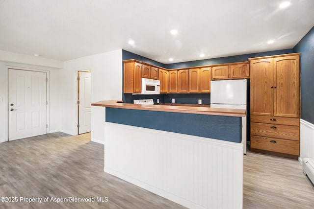 kitchen with white appliances, light wood-style flooring, recessed lighting, a peninsula, and light countertops