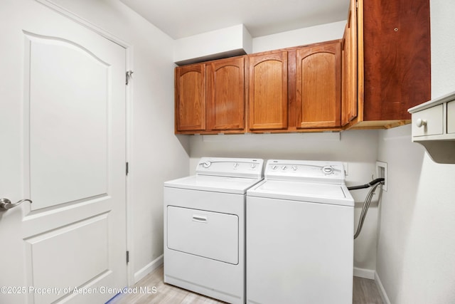 laundry area with cabinet space, separate washer and dryer, light wood finished floors, and baseboards