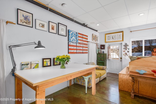 interior space with a drop ceiling, recessed lighting, and concrete flooring