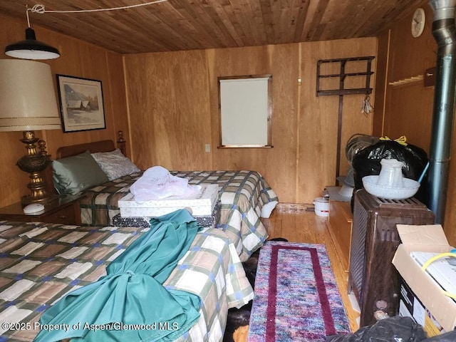 bedroom with wood ceiling, wood finished floors, and wooden walls