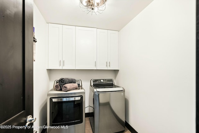 washroom with light tile patterned floors, washing machine and dryer, and cabinets