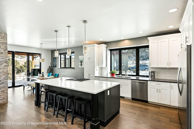 kitchen featuring a kitchen island, appliances with stainless steel finishes, pendant lighting, white cabinets, and decorative backsplash