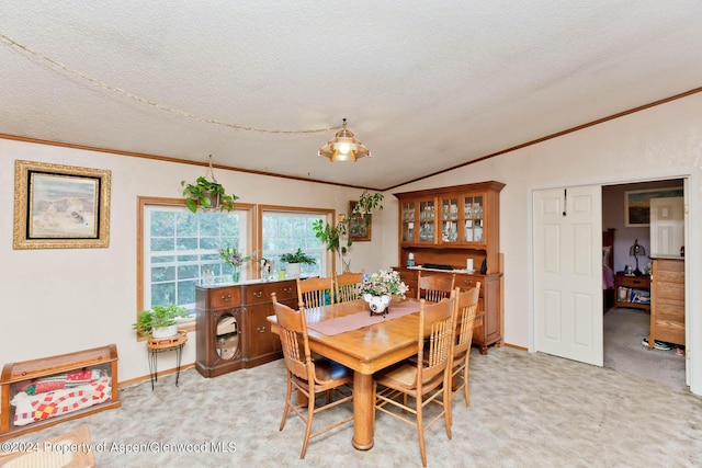 carpeted dining space with ornamental molding, a textured ceiling, and vaulted ceiling
