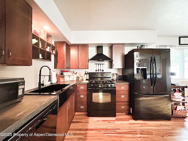 1111 Barclay St, Craig, CO 81625 - kitchen featuring wall chimney range hood, black appliances, light wood-type flooring, and brown cabinetry