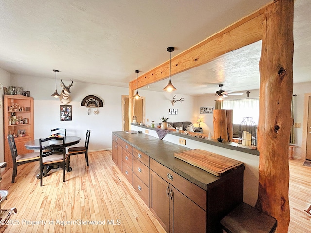 1111 Barclay St, Craig, CO 81625 - kitchen with dark countertops, light wood-type flooring, hanging light fixtures, ceiling fan, and beamed ceiling