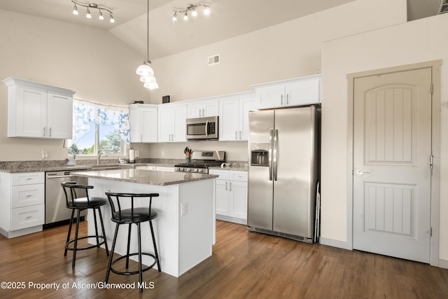 325 SE Cobblestone Ct, Cedaredge, CO 81413 - kitchen with stainless steel appliances, high vaulted ceiling, white cabinets, a center island, and a kitchen bar