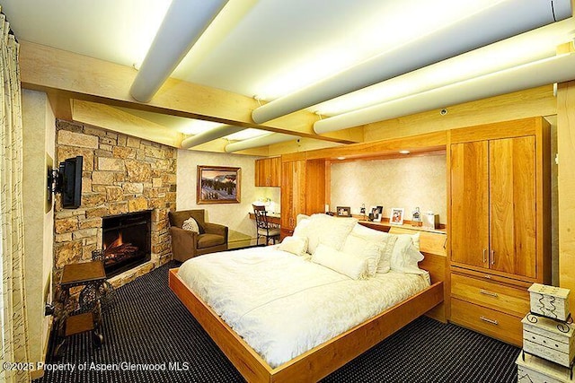 bedroom with a fireplace and beam ceiling