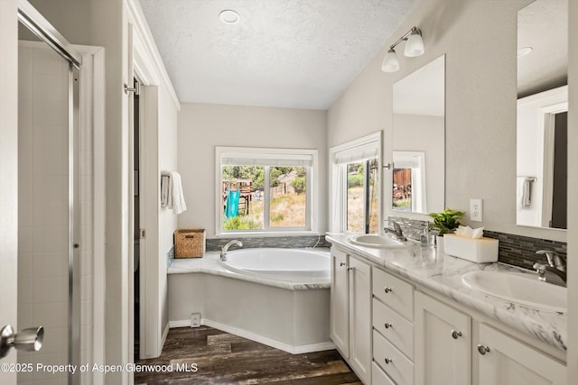 14 Fender Ln, Carbondale, CO 81623 - full bathroom with wood finished floors, double vanity, a bath, a textured ceiling, and a stall shower