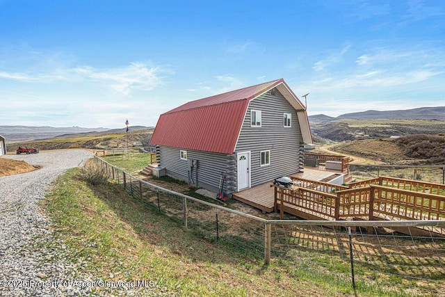 950 Highland Dr, Craig, CO 81625 - view of home's exterior featuring a gambrel roof, metal roof, a deck with mountain view, a barn, and fence
