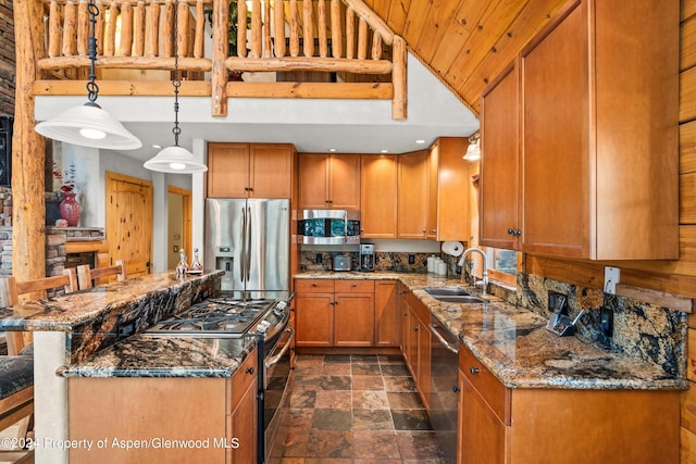 kitchen with pendant lighting, dark stone counters, sink, appliances with stainless steel finishes, and a kitchen bar