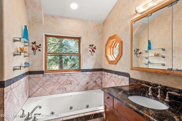 bathroom with tiled tub and vanity