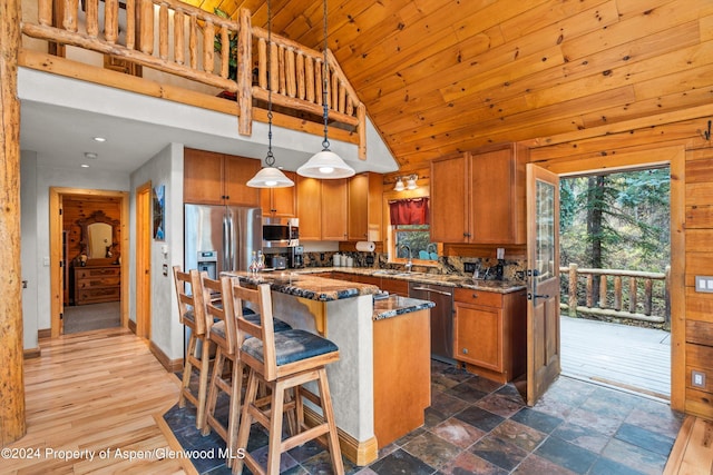 kitchen featuring a kitchen breakfast bar, stainless steel appliances, high vaulted ceiling, a center island, and hanging light fixtures