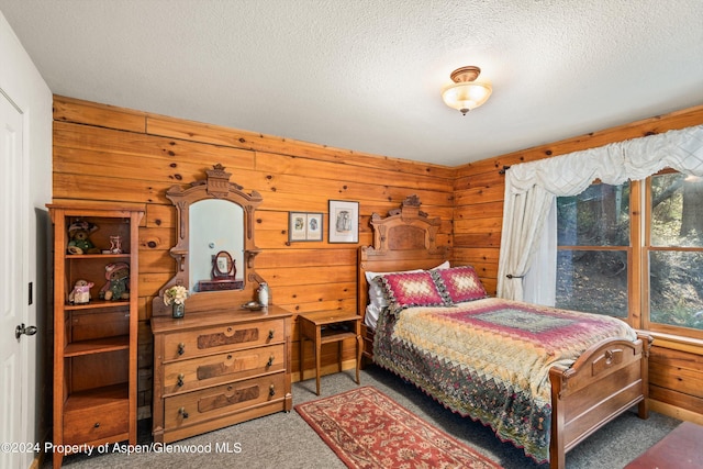 bedroom featuring wooden walls, carpet floors, and a textured ceiling