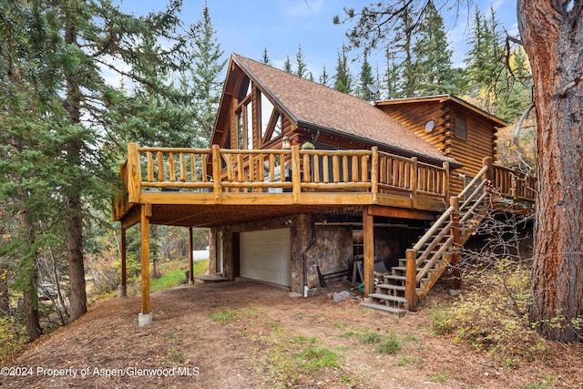 rear view of property featuring a garage and a wooden deck