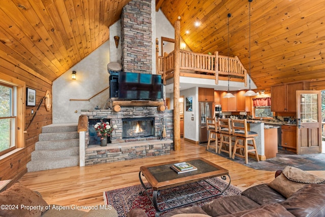 living room featuring wood ceiling, a stone fireplace, high vaulted ceiling, and wood-type flooring