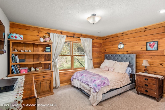 bedroom featuring a textured ceiling, light colored carpet, and wooden walls