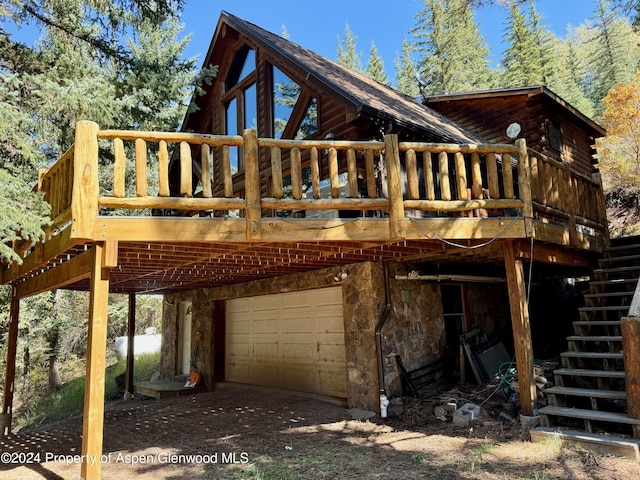 rear view of house with a garage and a wooden deck