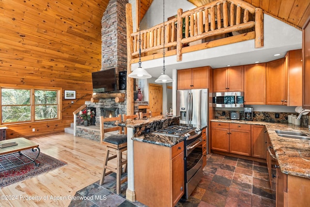 kitchen with a high ceiling, stainless steel appliances, pendant lighting, and sink