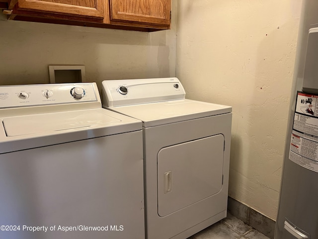 clothes washing area featuring cabinets, electric water heater, and separate washer and dryer