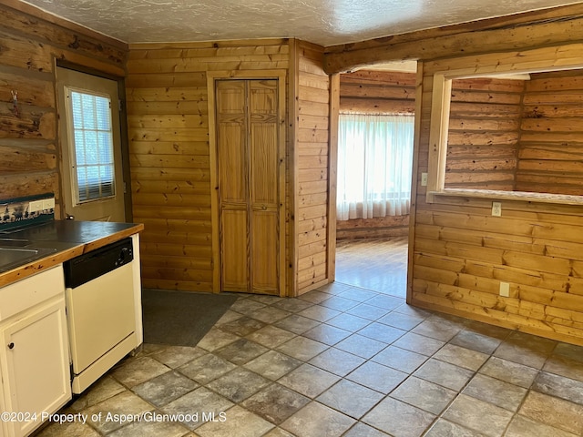 kitchen with white dishwasher, white cabinets, and log walls