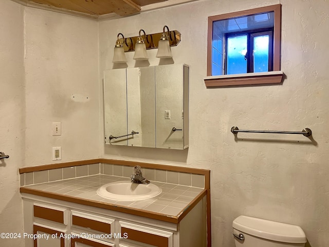 bathroom with vanity, tasteful backsplash, and toilet