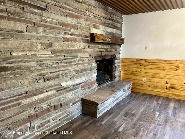 unfurnished living room with a fireplace, wooden walls, and dark wood-type flooring