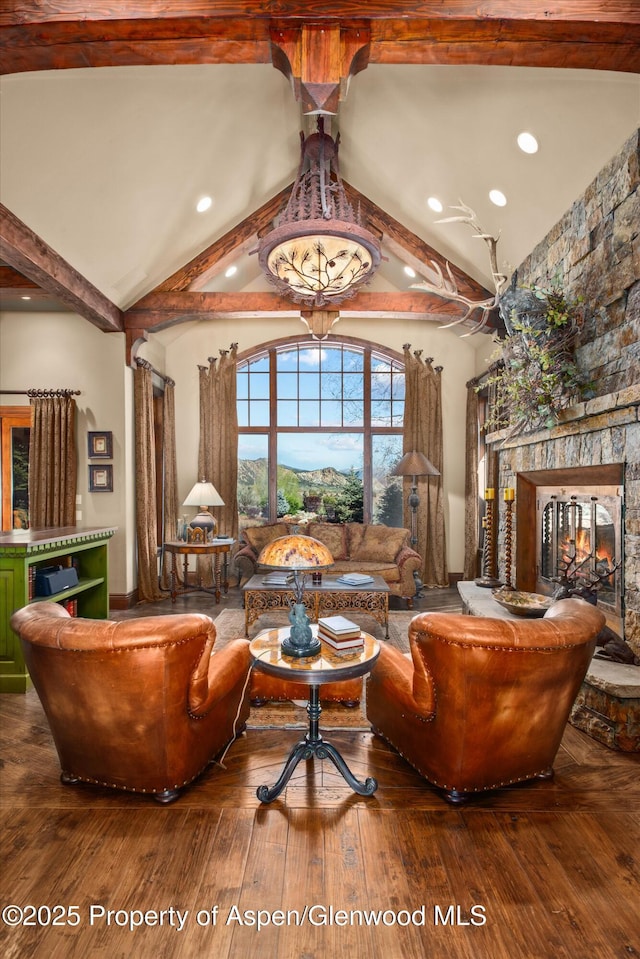 interior space with a stone fireplace, vaulted ceiling with beams, and hardwood / wood-style floors