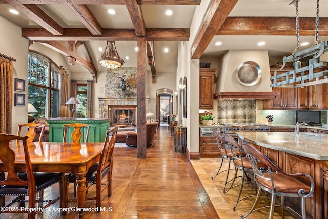 dining area featuring a fireplace, light wood-type flooring, beam ceiling, baseboards, and recessed lighting
