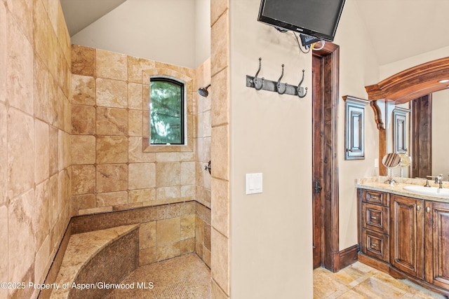full bathroom featuring vanity, a tile shower, and lofted ceiling