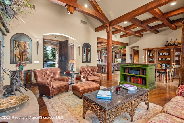 living room with arched walkways, wood finished floors, a towering ceiling, beamed ceiling, and visible vents