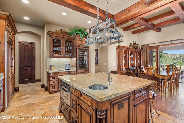kitchen with beam ceiling, glass insert cabinets, beverage cooler, recessed lighting, and a sink