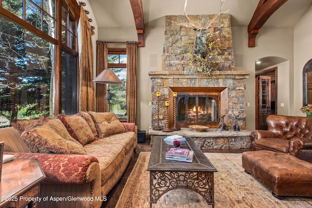 living room featuring arched walkways, a fireplace, and beam ceiling