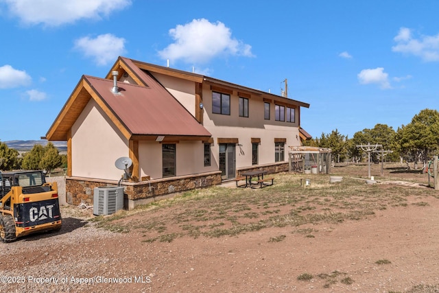76 County Road 60b, Maybell, CO 81640 - rear view of property with central AC unit, metal roof, stucco siding, and stone siding