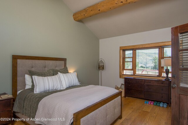 bedroom featuring vaulted ceiling with beams and light wood-type flooring