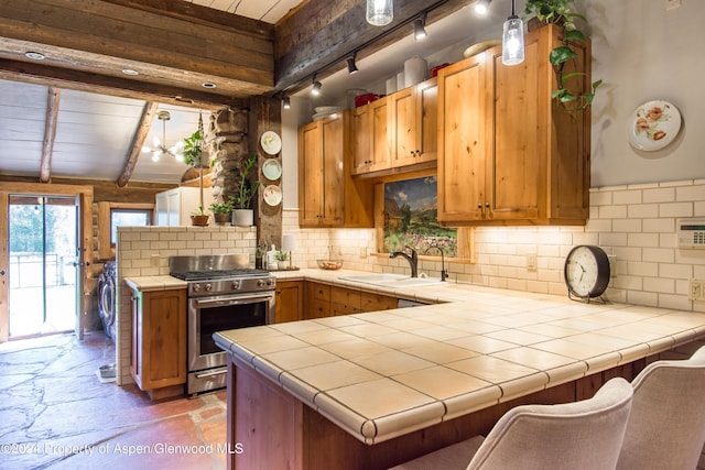 1150 Capitol Creek Rd, Snowmass, CO 81654 - kitchen with stainless steel range with gas cooktop, a peninsula, tile countertops, light stone finish floors, and beamed ceiling