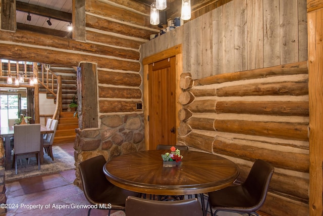 dining room featuring beamed ceiling and log walls