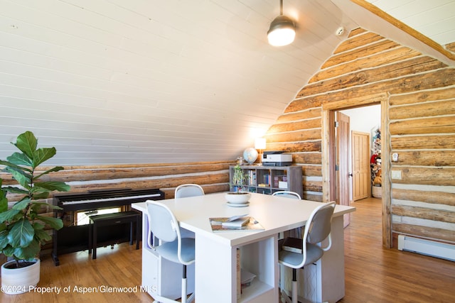 dining room featuring rustic walls, hardwood / wood-style floors, vaulted ceiling, and a baseboard heating unit