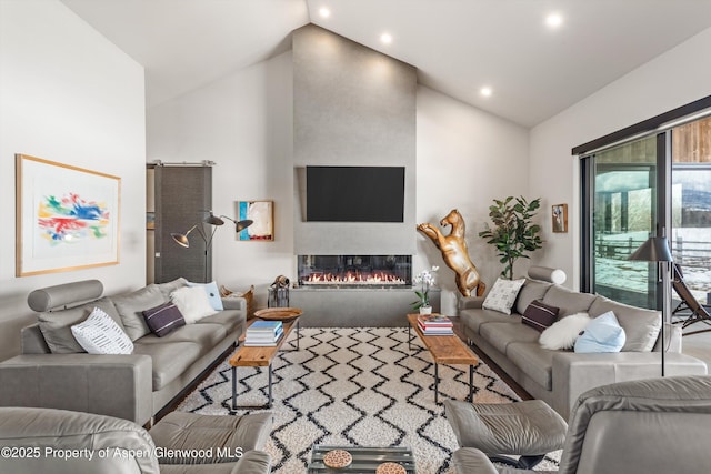 living room featuring a barn door, wood finished floors, vaulted ceiling, a fireplace, and recessed lighting