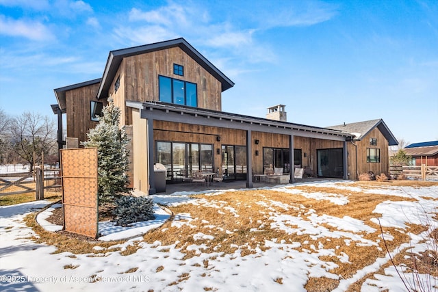 snow covered property with a patio area and fence