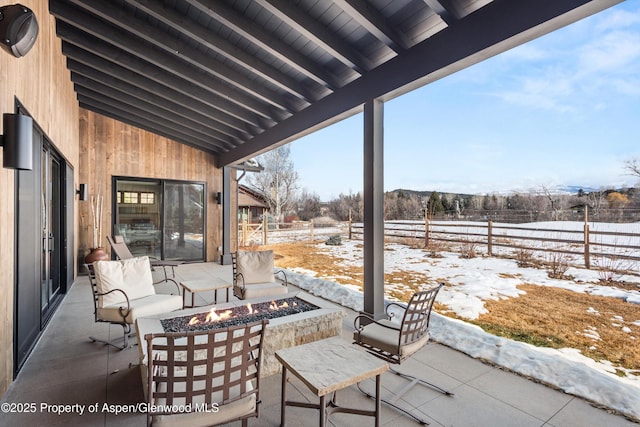 snow covered patio featuring fence and a fire pit