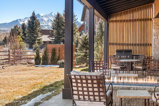 view of patio with outdoor lounge area, grilling area, fence, and a mountain view