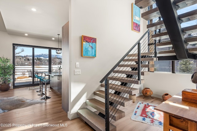 stairway with baseboards, wood finished floors, and recessed lighting