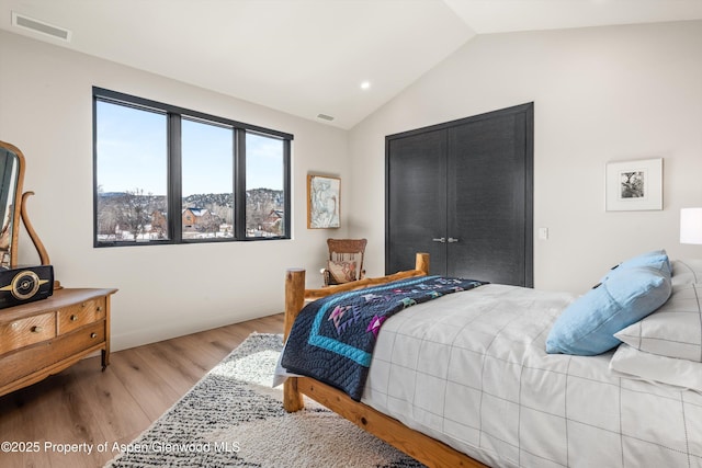 bedroom with lofted ceiling, visible vents, baseboards, and wood finished floors